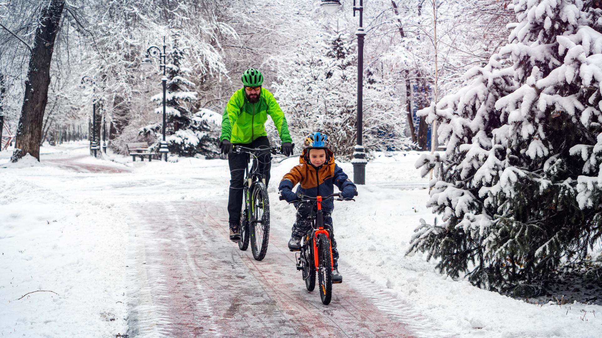 a man and child cycling on a snow covered path