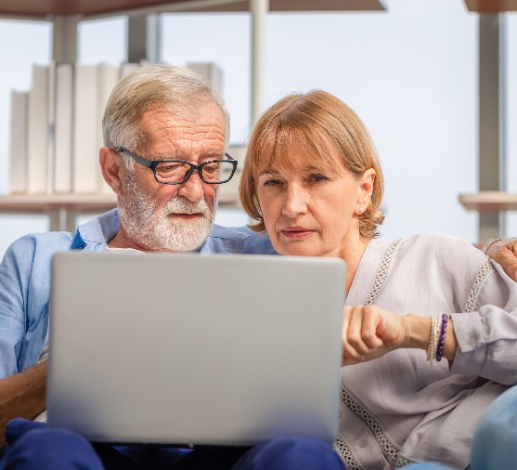 An older couple look at bills on their computer concerned