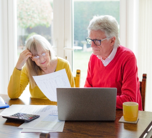 Senior couple looking concerned at energy bills and computer