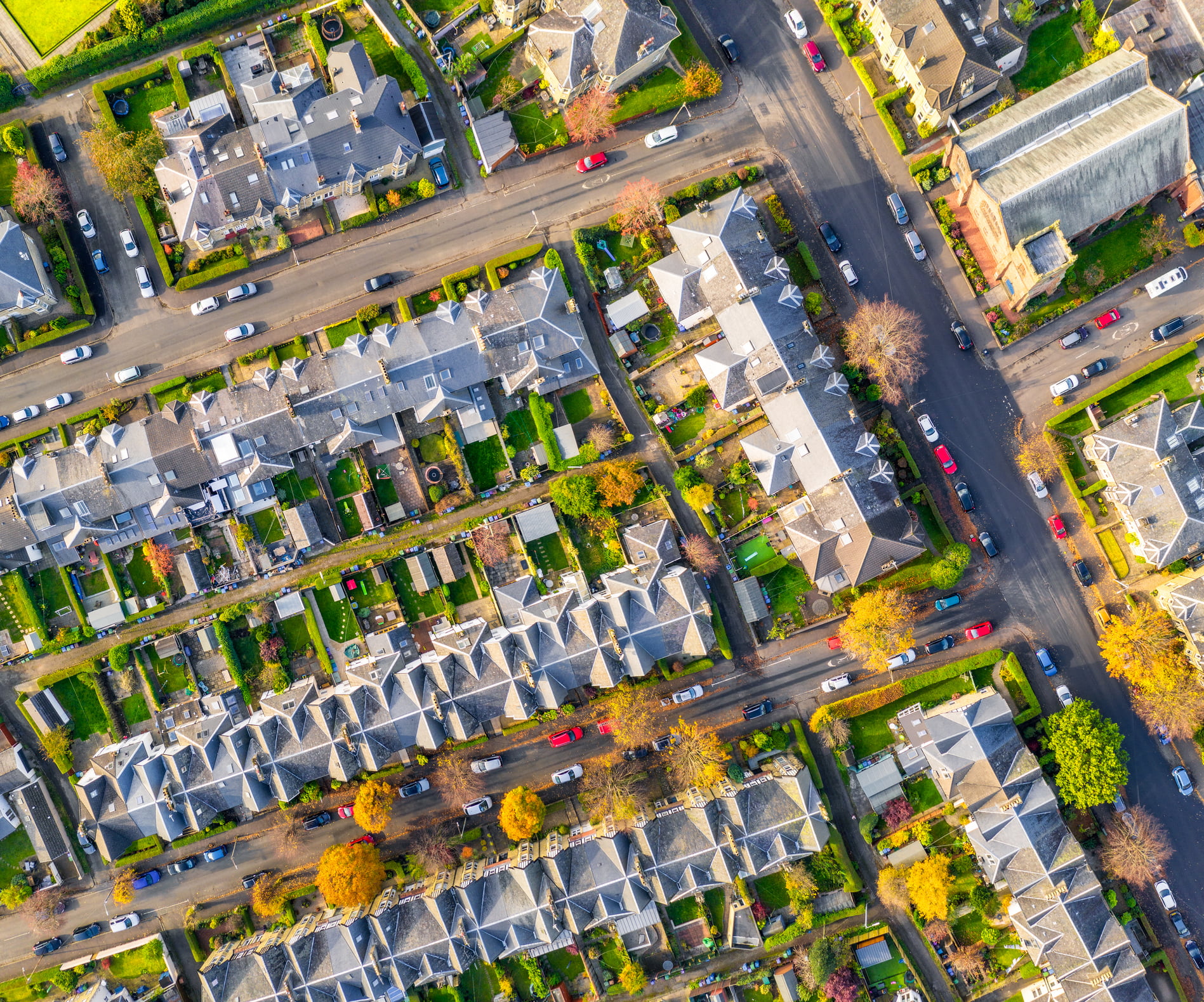 A birdseye view of attached houses in neat rows. Each house has a neat garden with a few trees.