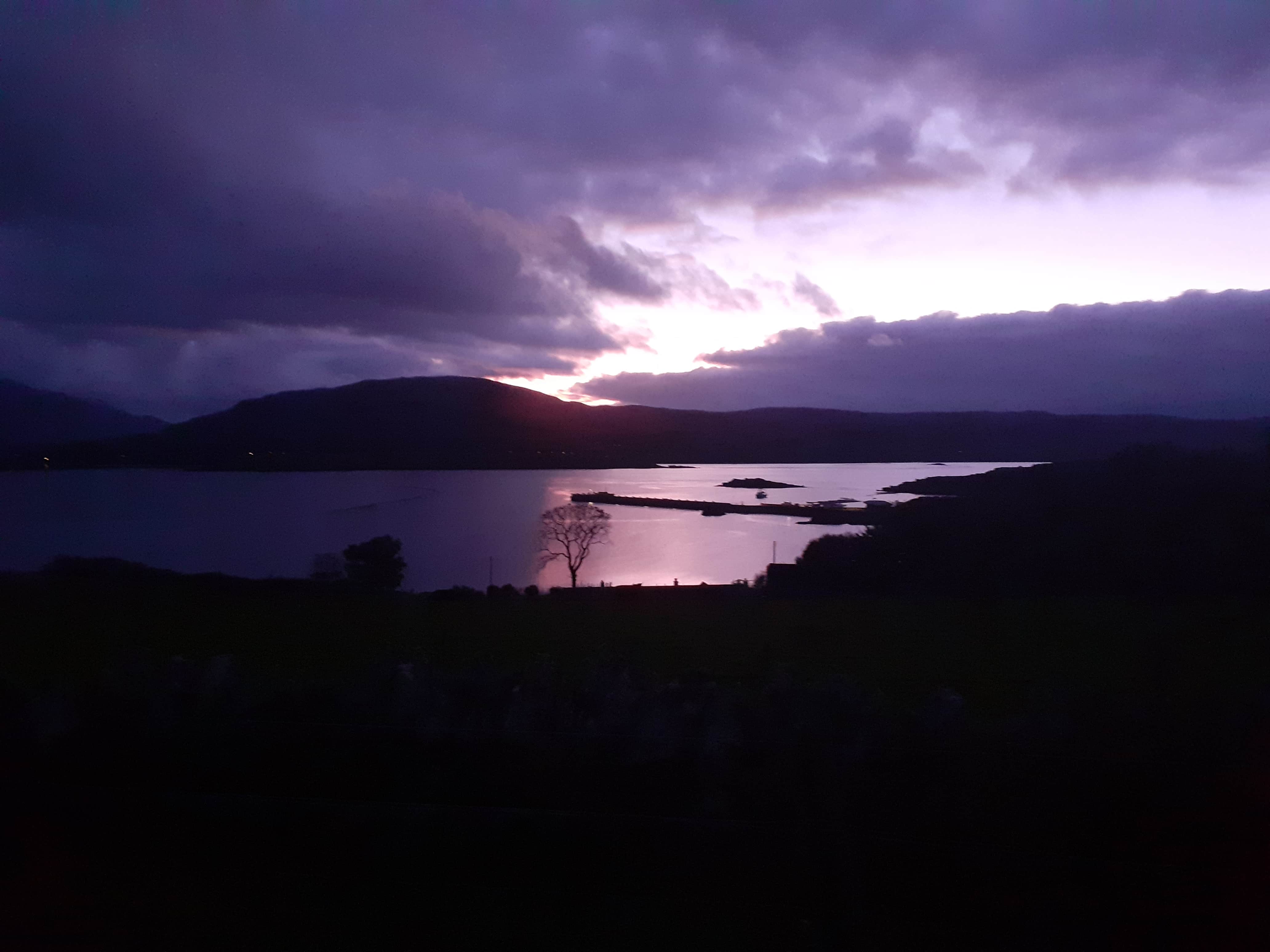 A view out to sea with hills in the background on the isle of Raasay. There is a moody atmosphere at sunrise.