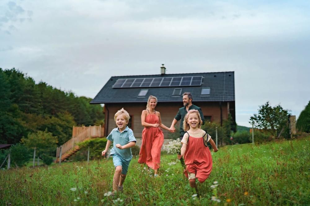 Young family playing in front of their solar powered home