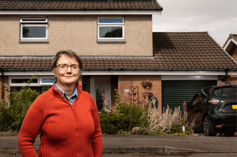 Philippa standing in front of her house smiling